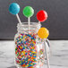 A jar filled with colorful lollipops on a counter.