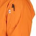 A person wearing an orange Uncommon Chef 3/4 length sleeve chef coat with a black pen in the pocket.