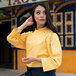A woman wearing a yellow Uncommon Chef sunflower chef coat with 3/4 length sleeves.