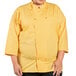 A plus size woman wearing a yellow Uncommon Chef 3/4 length sleeve chef coat with sunflowers.