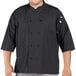 A man wearing a black Uncommon Chef 3/4 length sleeve chef coat with side vents.