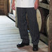 A person wearing Uncommon Chef chalk stripe chef pants in black and white.