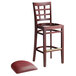 A Lancaster Table & Seating mahogany wood bar stool with a burgundy vinyl cushion on the seat.