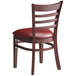 A Lancaster Table & Seating wooden chair with a burgundy vinyl cushion.