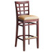 A Lancaster Table & Seating mahogany wood bar stool with a light brown vinyl seat.