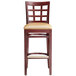 A Lancaster Table & Seating mahogany wood bar stool with a light brown vinyl seat.