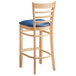 A Lancaster Table & Seating wooden bar stool with a navy blue cushion on the seat.