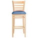 A Lancaster Table & Seating wooden ladder back bar stool with a navy cushion on the seat.