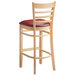 A Lancaster Table & Seating wood ladder back bar stool with a burgundy vinyl seat.