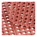 A close-up of a red rubber Choice anti-fatigue floor mat with holes.