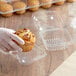 A hand holding a muffin in a clear plastic container.