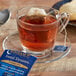 A glass cup of Bigelow Sweet Dreams herbal tea with a tea bag on a saucer.