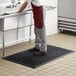 A man standing on a black Choice rubber ridge-scraper mat in a kitchen.