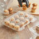 A hand putting mini muffins in a clear plastic container with 12 compartments.