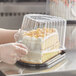 A person in gloves putting a cake into a Choice plastic container.