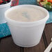 A white Dart foam container filled with soup.