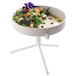 A Cal-Mil white plate stand holding a bowl of salad on a table.