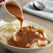 A bowl of mashed potatoes with LeGout brown gravy.