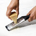 A person grating cheese on an OXO stainless steel grater.