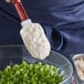A person using a spatula to spread Hellmann's mayonnaise on a bowl of green onions.