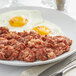 A plate of LeGout Corned Beef Hash with eggs and a knife and fork.