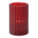 A Hollowick Ruby glass candle holder with a lit red candle in it.