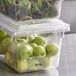 A stack of Vigor clear polycarbonate food storage boxes filled with green apples and greens.