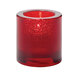 A Hollowick round ruby glass tealight holder with a lit candle inside.