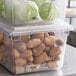 A clear plastic Vigor food storage box filled with potatoes and vegetables.