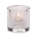 A Hollowick clear glass tealight holder with a lit candle.