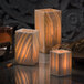 Three Hollowick Luxor alabaster tealight candle holders on a table with lit candles.