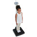 A young girl stands on a Cardinal Detecto digital clinical scale.