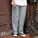 A person wearing Uncommon Chef houndstooth chef pants and sneakers.