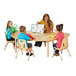 A woman reading a book to children sitting at a Jonti-Craft adjustable height table.