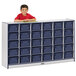 A young boy in a red shirt standing next to a Rainbow Accents navy storage cabinet with trays.