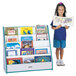 A young girl standing next to a Rainbow Accents teal book rack filled with books.