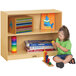 A young girl sitting next to a Jonti-Craft wood shelf unit with toys on it.