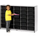 A young girl standing next to a Rainbow Accents black storage cabinet with black bins on it.