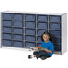 A young girl sitting on the floor reading a book next to a blue Rainbow Accents storage cabinet.