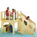 A group of kids playing on a Jonti-Craft wooden play loft with a wooden slide and staircase.