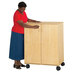 A woman pushing a Jonti-Craft wood classroom supply cabinet.