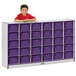 A boy standing next to a Rainbow Accents purple and white storage cabinet with purple trays.