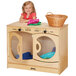 A little girl smiling while sitting on a Jonti-Craft wood play laundry center.