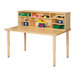 A Jonti-Craft wooden work table with a maple top and storage shelves full of toys.