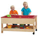 A group of children playing with a Jonti-Craft wood sensory table with toys.