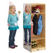A little girl in a blue jacket and white gloves standing in front of a Jonti-Craft Dress-Up Locker mirror.