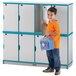 A boy holding a blue lunch bag standing next to a Rainbow Accents teal double stack locker.