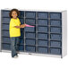A young girl standing next to a Rainbow Accents navy storage unit with blue bins.