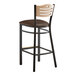 A Lancaster Table & Seating bar stool with a brown vinyl seat and wood back.