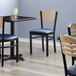 Lancaster Table & Seating Black Finish Bistro Chair with 2 1/2" Navy Vinyl Padded Seat and Natural Wood Back Main Thumbnail 1